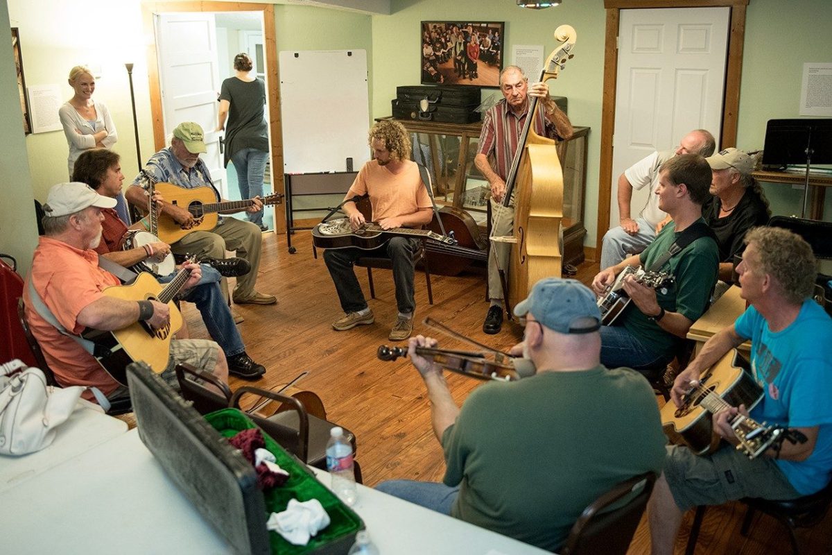 A group of people form a circle with instruments and do a jam session.