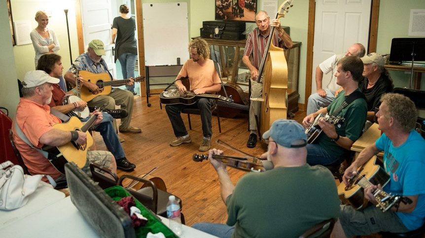 A group of people form a circle with instruments and do a jam session.