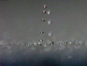 An image of water droplets jumping off of a surface.