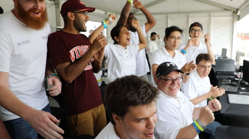 In the photo, a team of people cheer as they look to something out of frame.