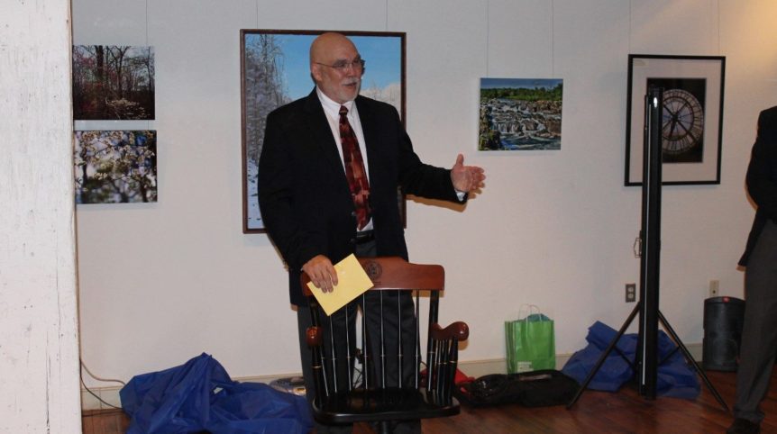 A man stands in the front of a room giving a speech to a group.