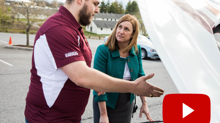 A screenshot of a video still featuring Virginia Tech College of Engineering Dean Julia Ross and a student looking under the hood of a car.