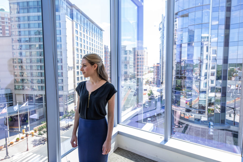 A photo of a young woman staring out windows into a busy cityscape.