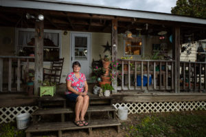 A photo of a woman sitting on her decorated back porch.