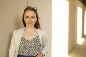 A photo of a woman looking into the camera with her hand on her hip, looking determined.